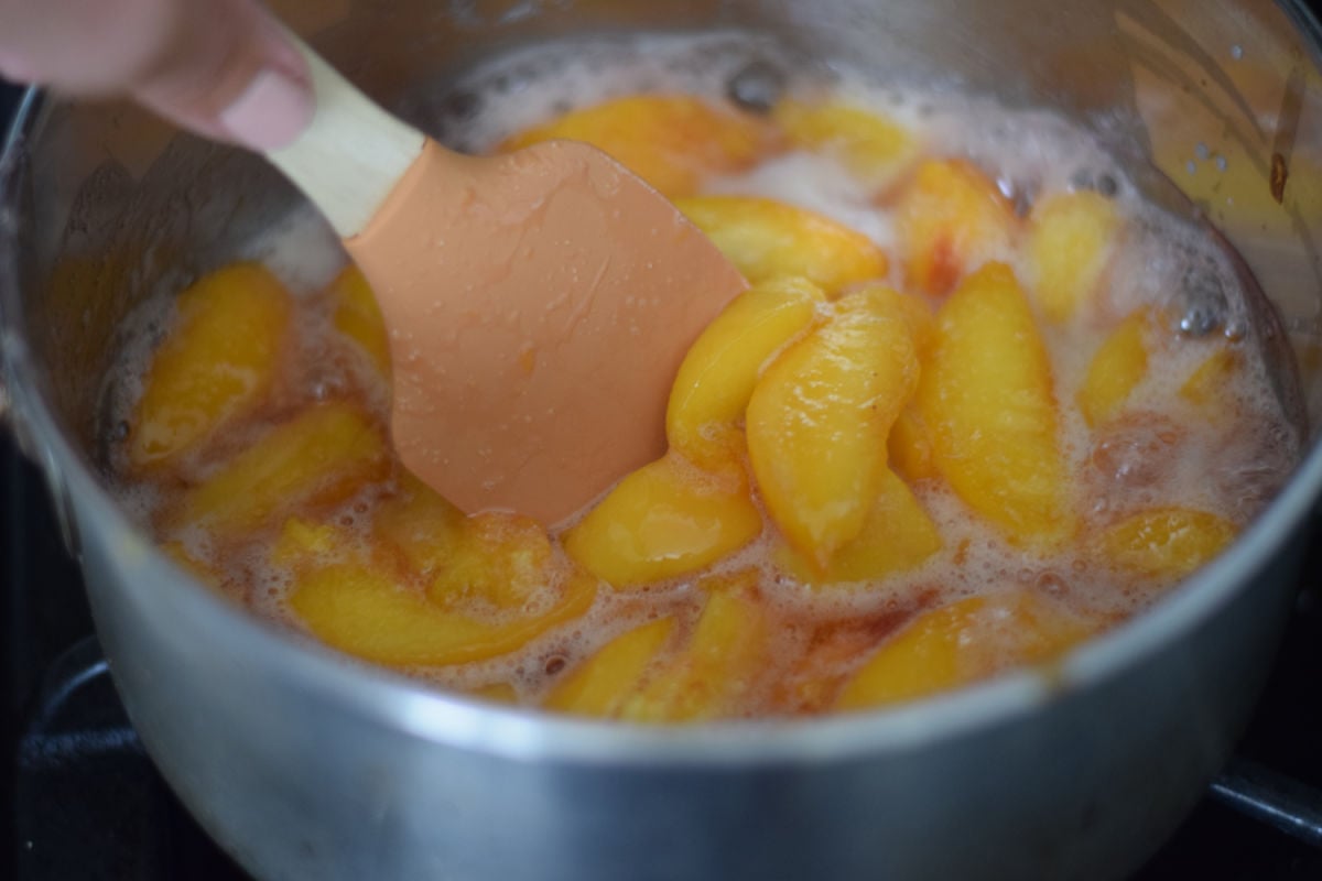 stirring peaches while making a syrup