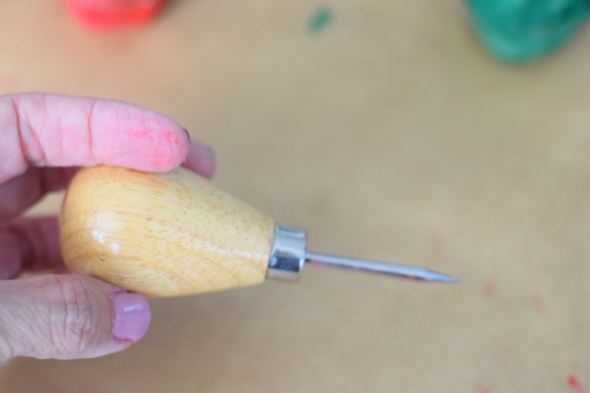 using an awl tool to poke holes for craft 