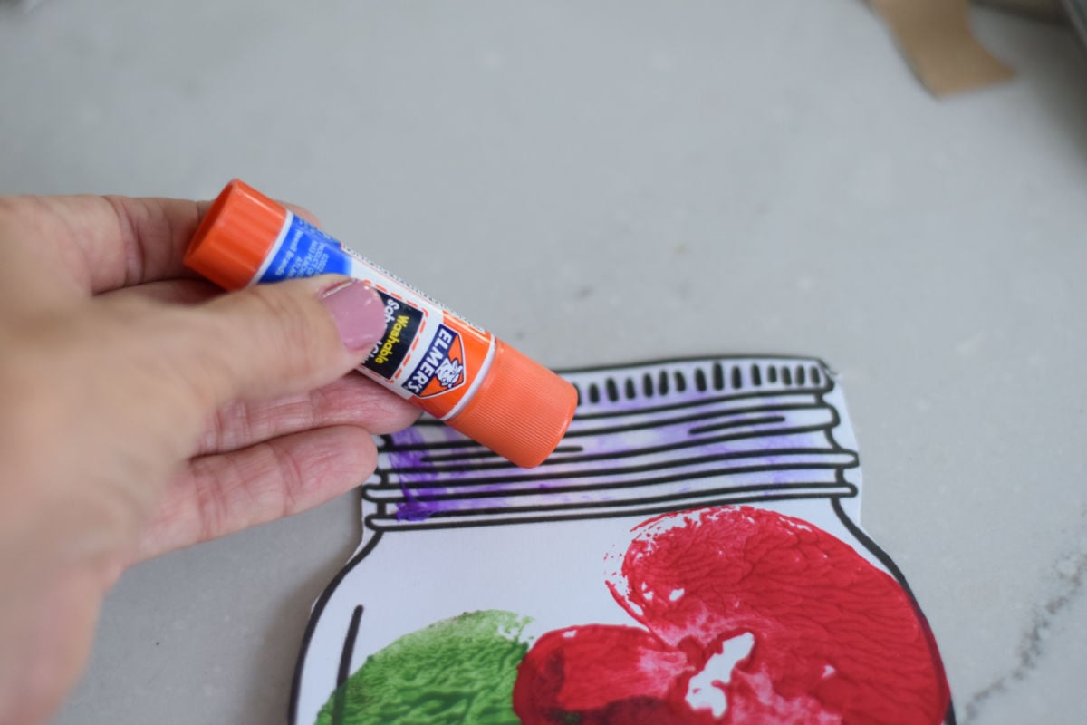 adding glue to the mason jar printable for the paper lid on the apple craft 