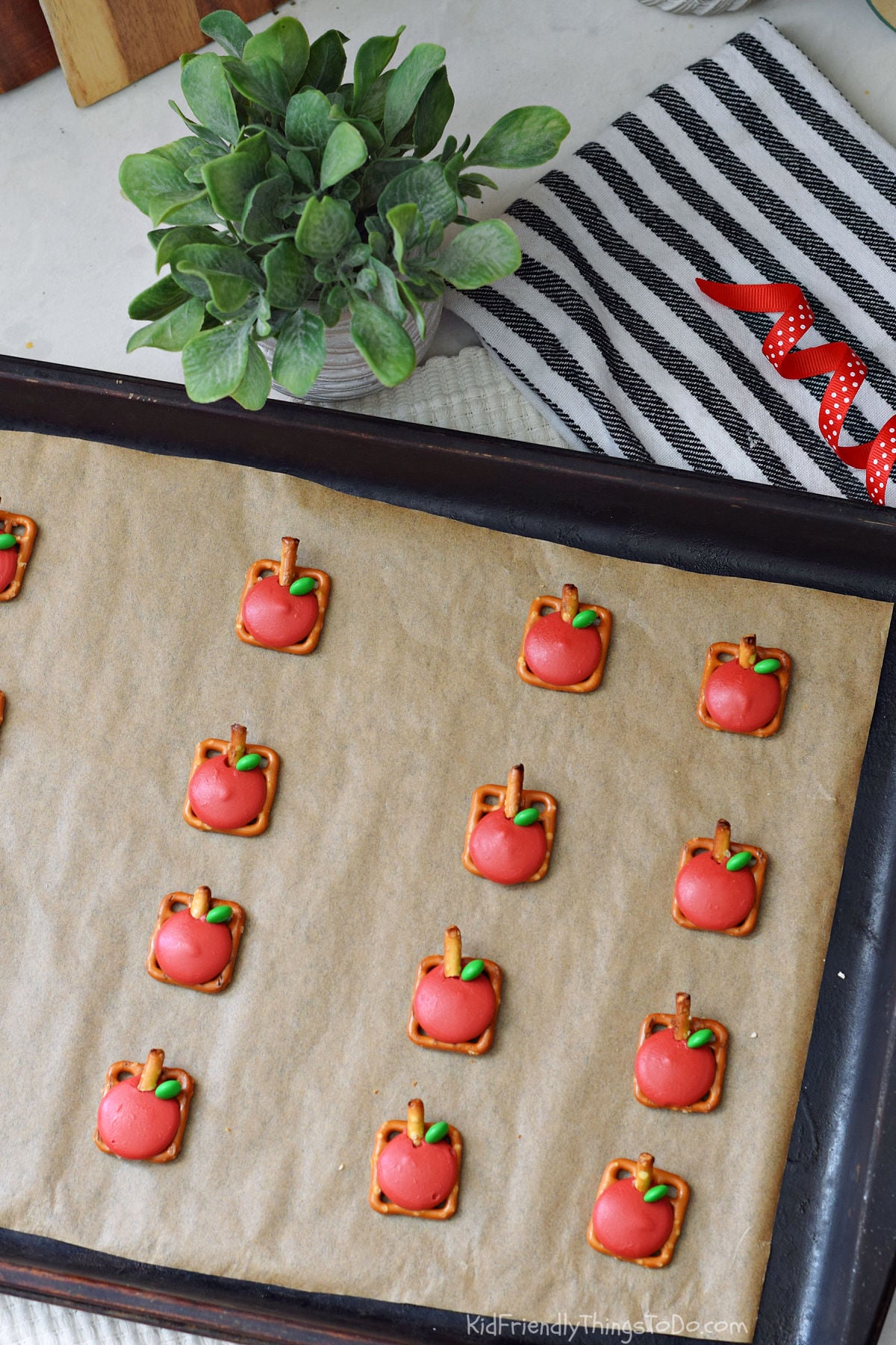 Apple Pretzel Bites fall snack fresh out of the oven, arranged on a parchment-lined baking sheet with pretzel stems and green M&M leaves