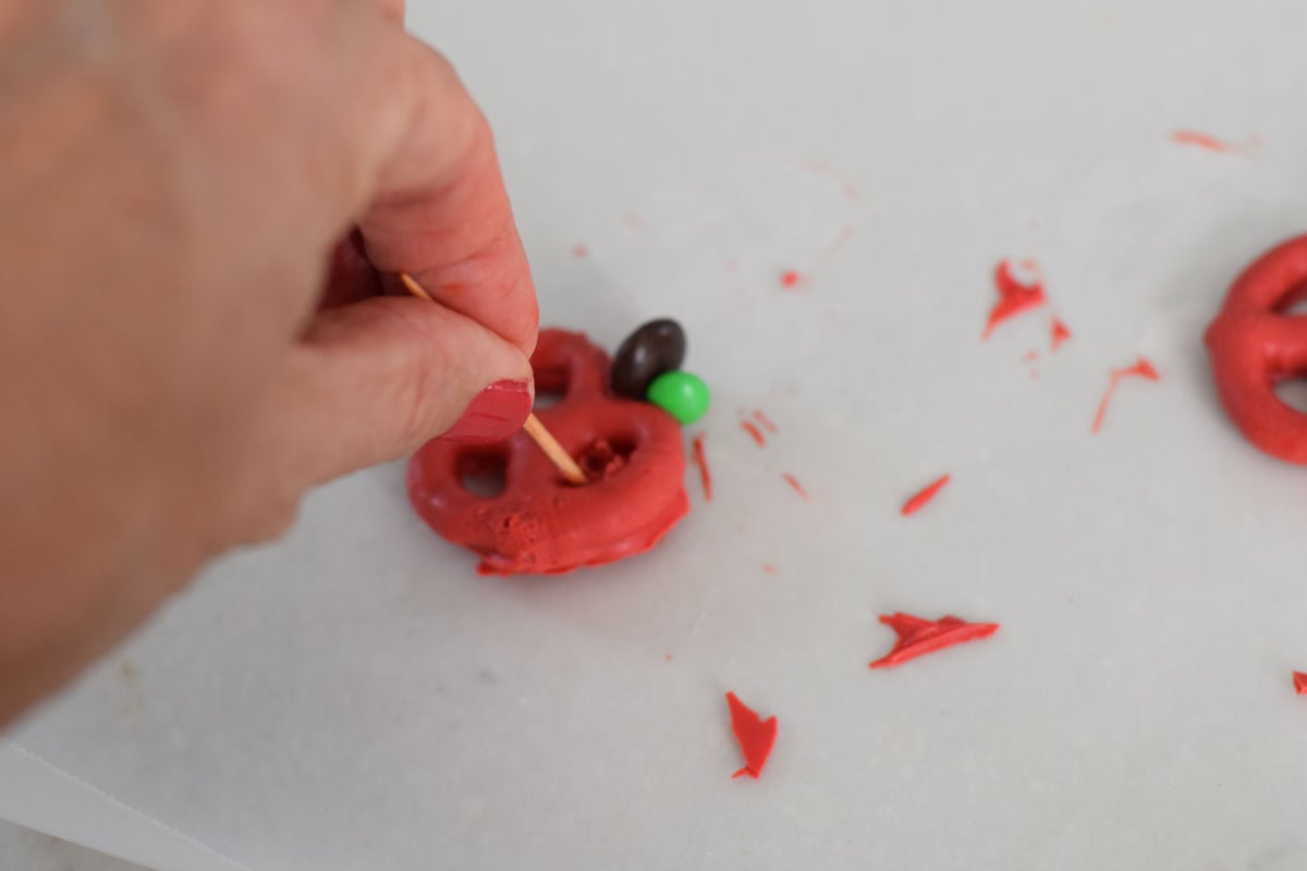 using a toothpick to clean up chocolate dipped pretzel apple