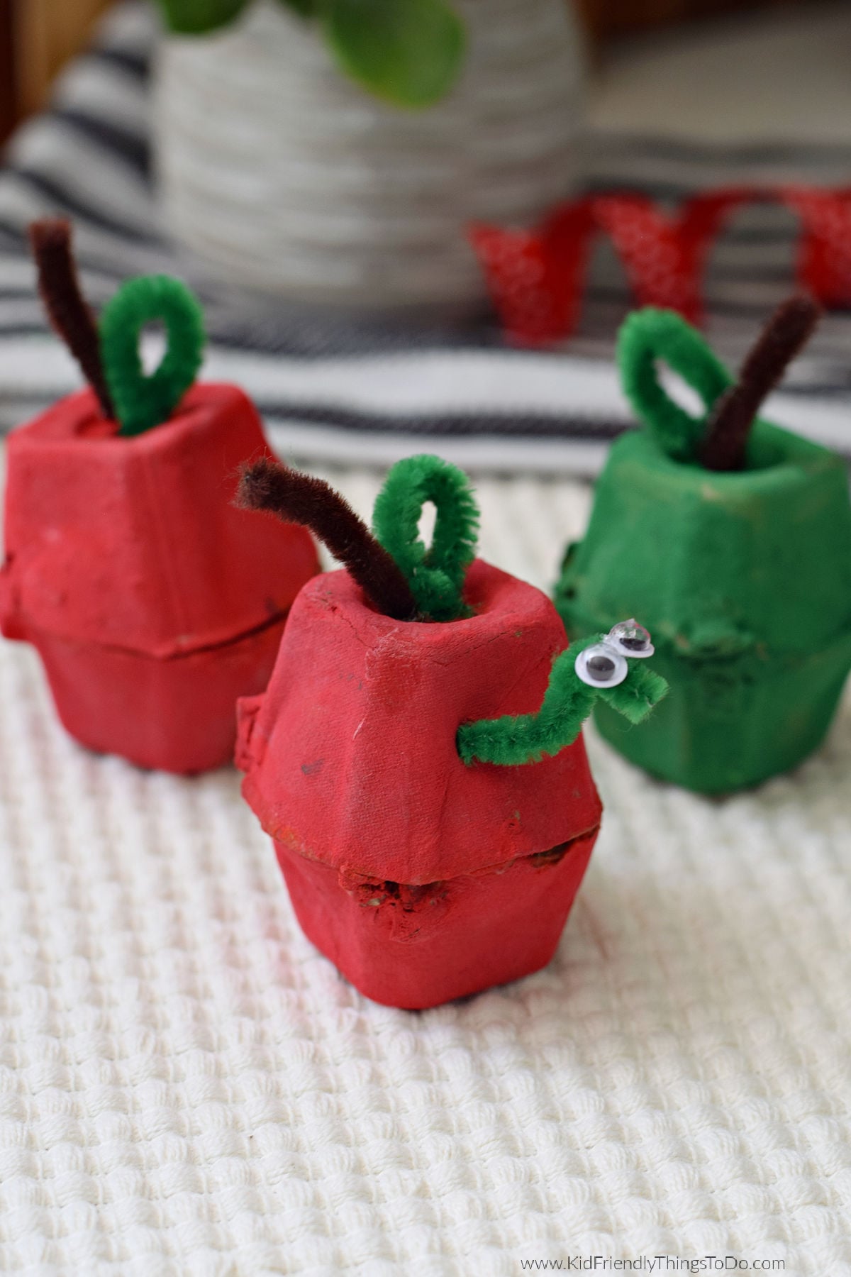 Egg carton apple craft with a pipe cleaner worm, stem, and leaf for kids to make in the fall