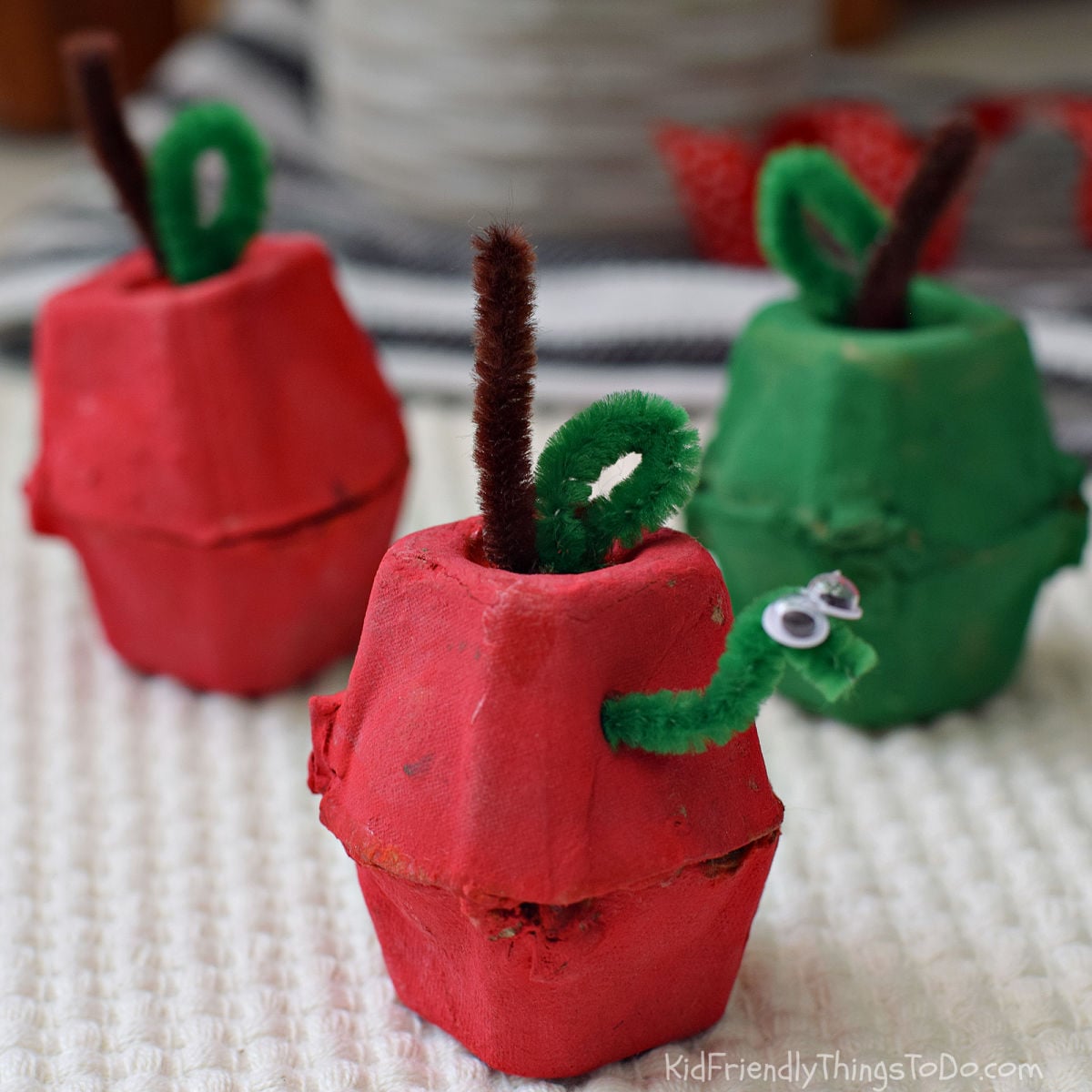 Egg carton apple craft for kids with a pipe cleaner worm, stem, and leaf