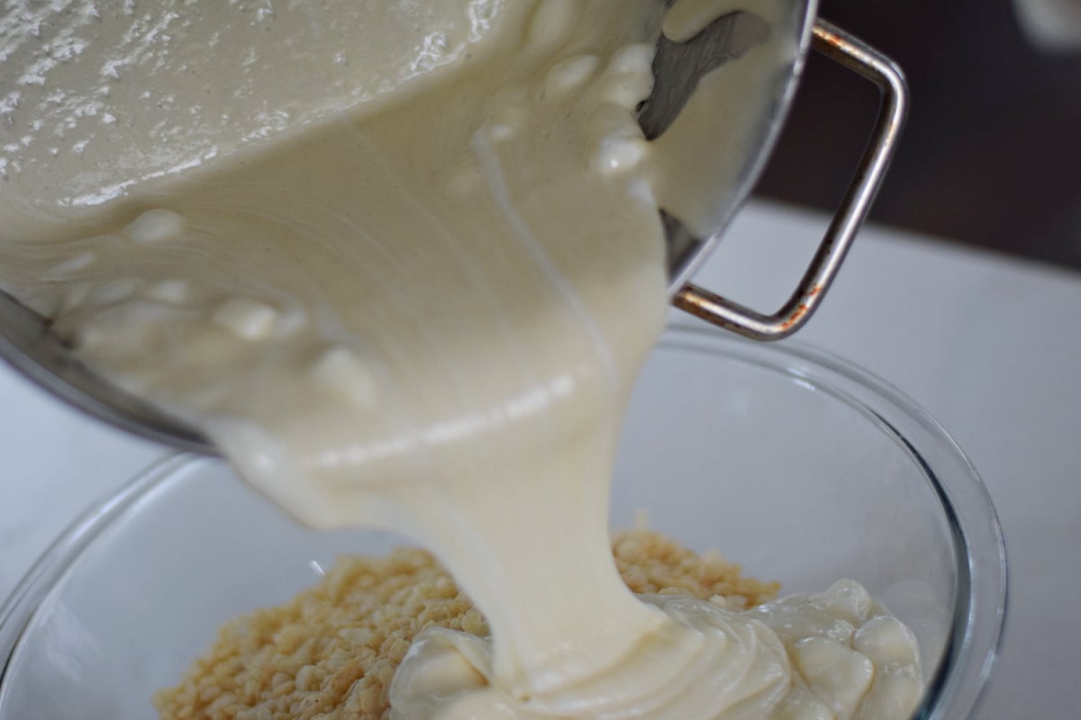 Melted marshmallow mixture being poured over Rice Krispies cereal