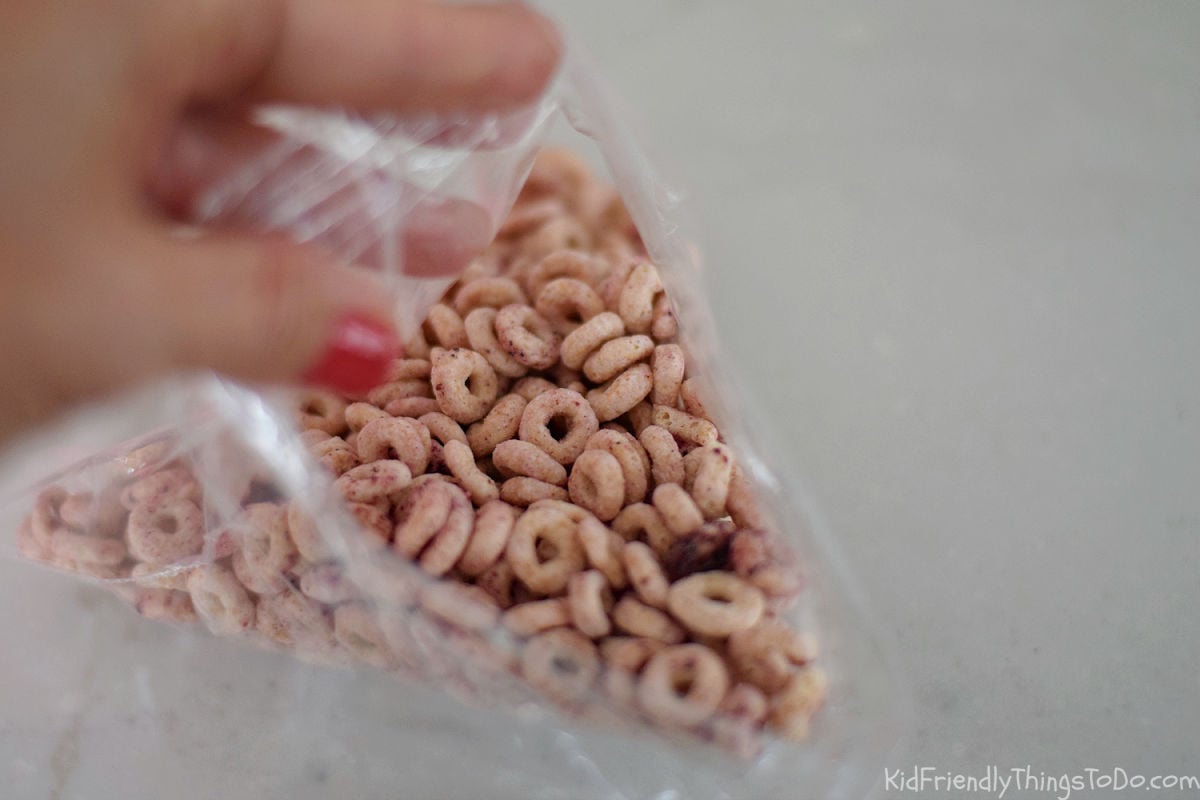 filling snack bag with cheerios for apple themed snack for kids 