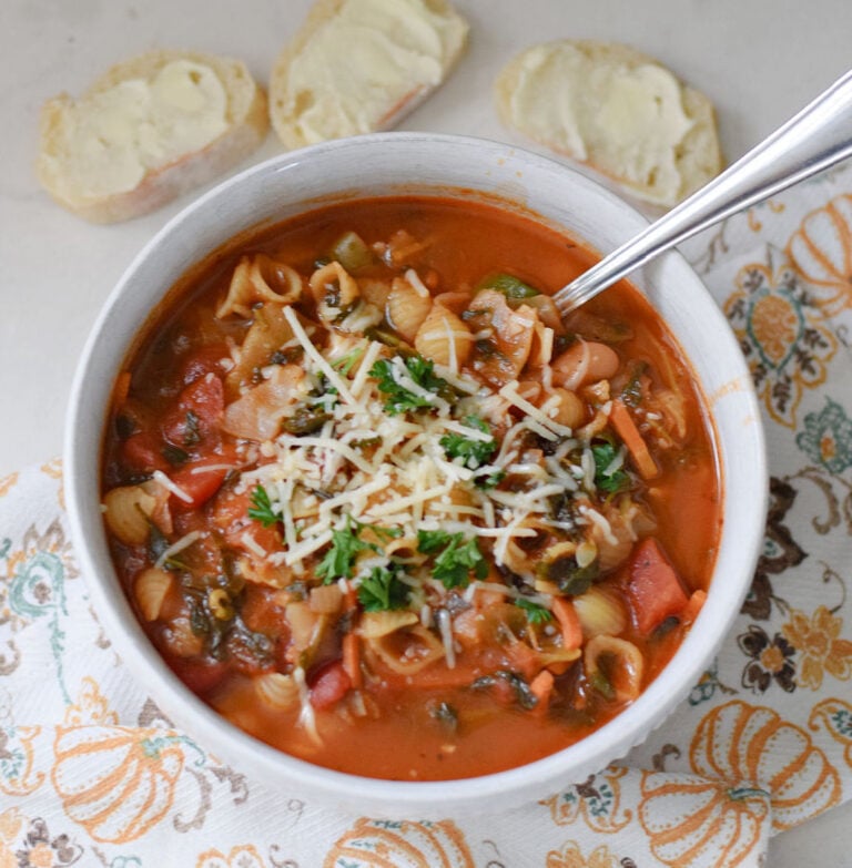 olive garden's copycat minestrone soup in bowl with spoon and slices of bread nearby