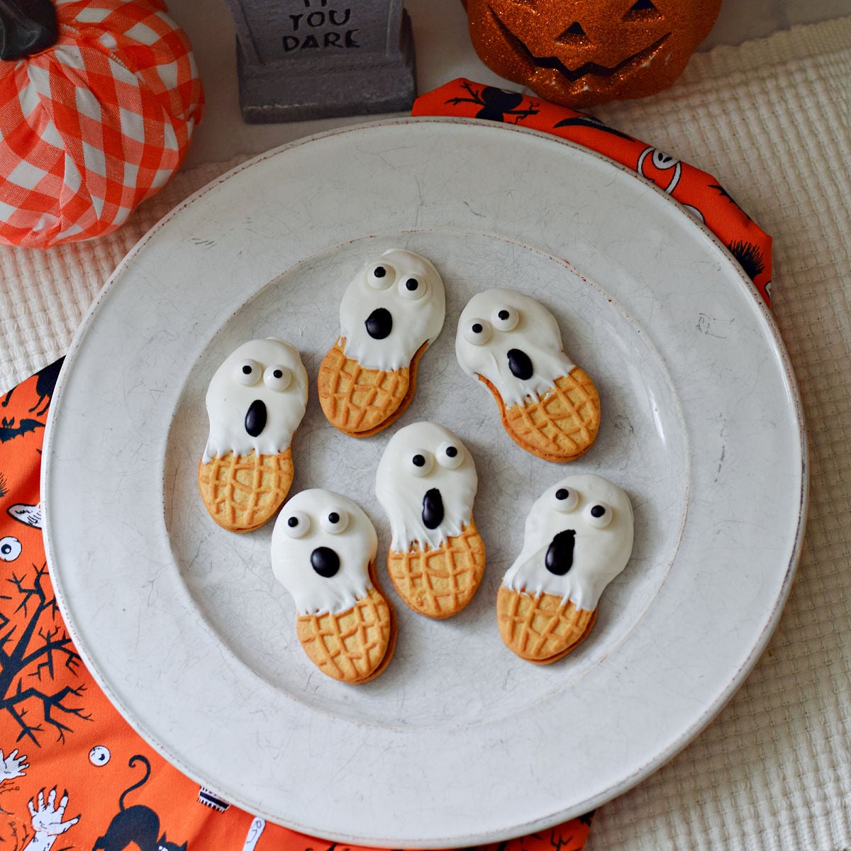Nutter Butter ghost cookies with candy eyes and surprised faces on a white plate