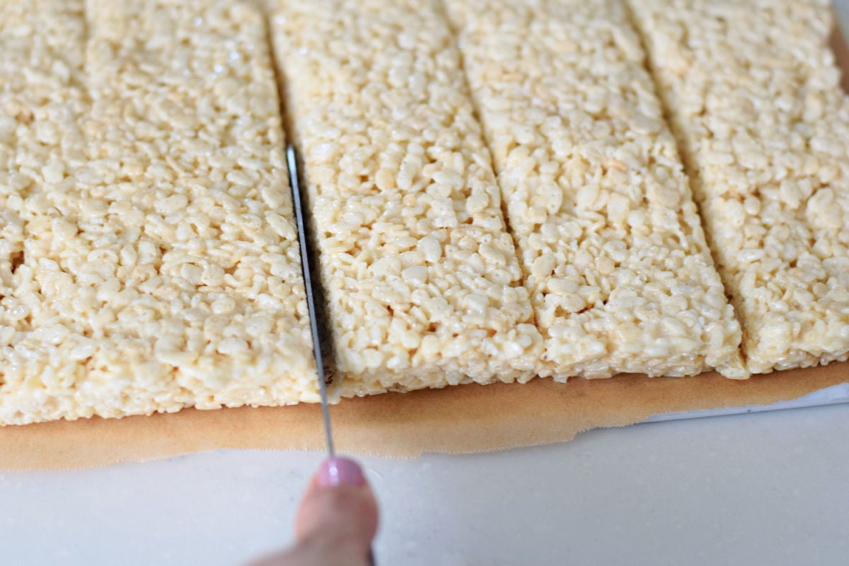 Rice Krispie Treats being cut into squares with a serrated knife