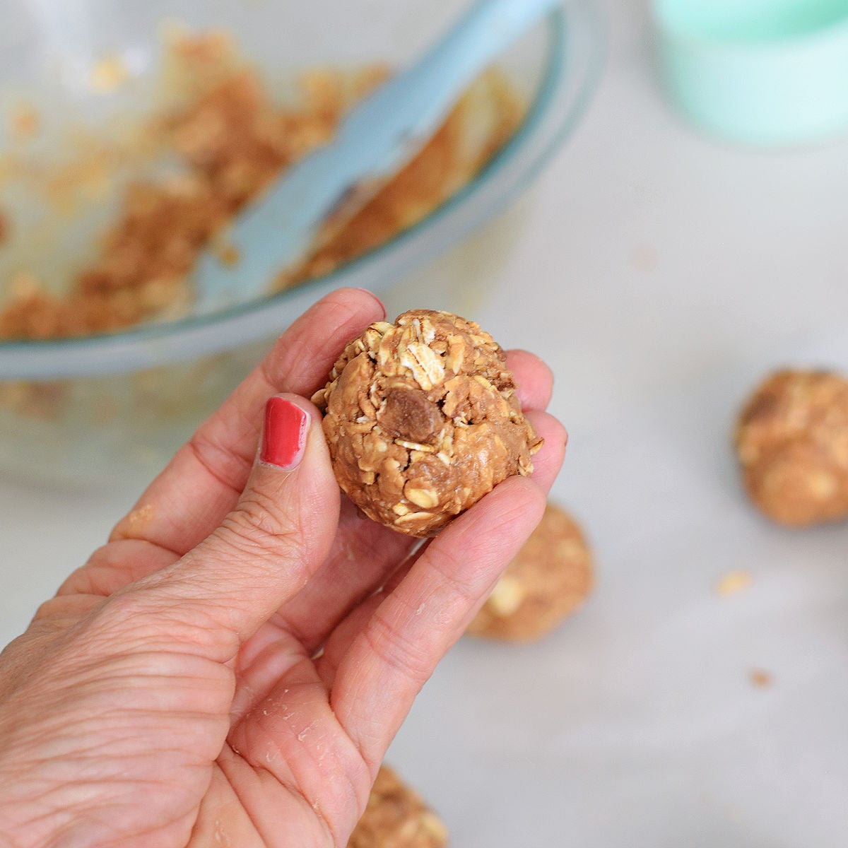 holding no-bake peanut butter chocolate protein ball in hand