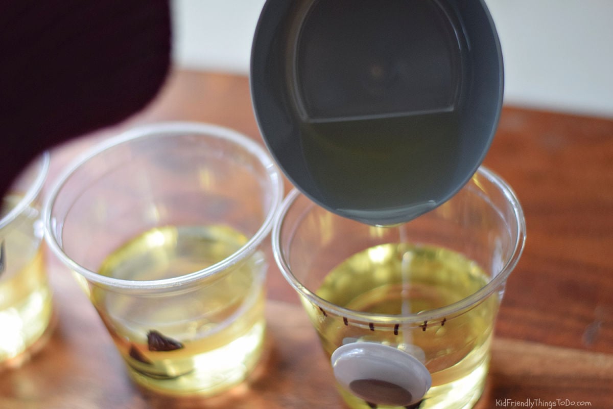 Pouring vegetable oil from a measuring cup into a clear monster cup.