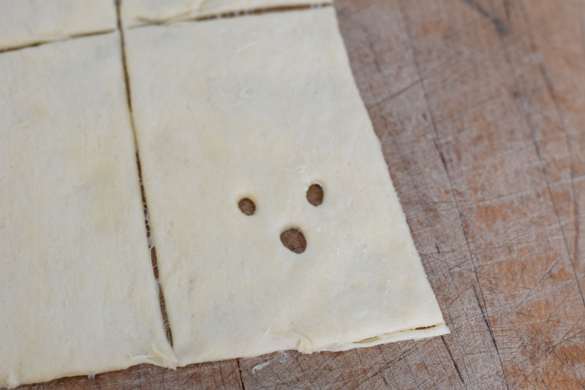 ghosts in a blanket crescent roll dough with ghost face cut out 