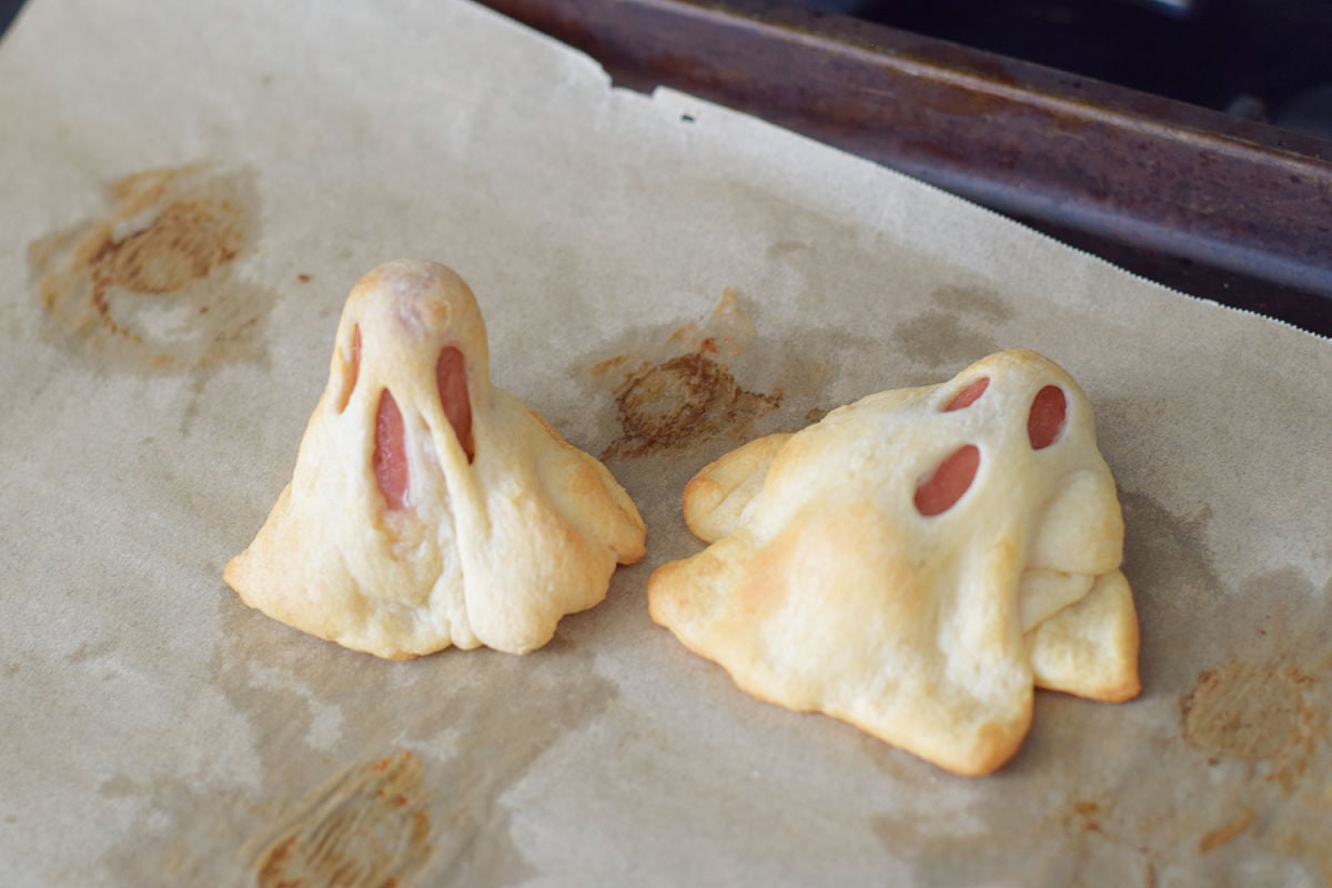 An upright Ghost in a Blanket with stretched eyes and mouth beside a ghost that tipped over during baking.
