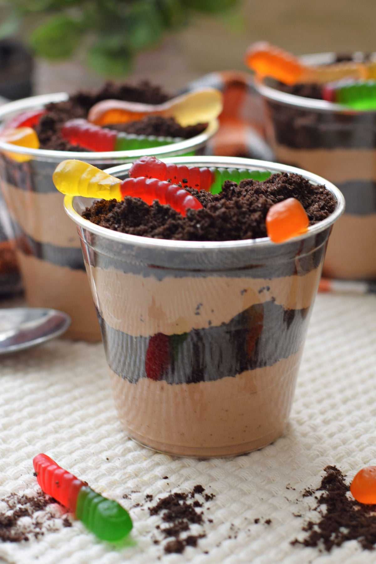  Dirt cups with layers of chocolate pudding and crushed Oreos topped with colorful gummy worms.