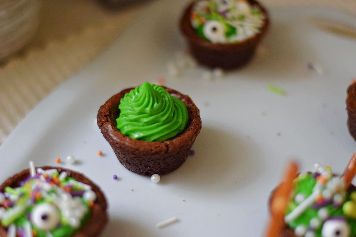  Mini brownie cauldrons filled with piped green frosting.
