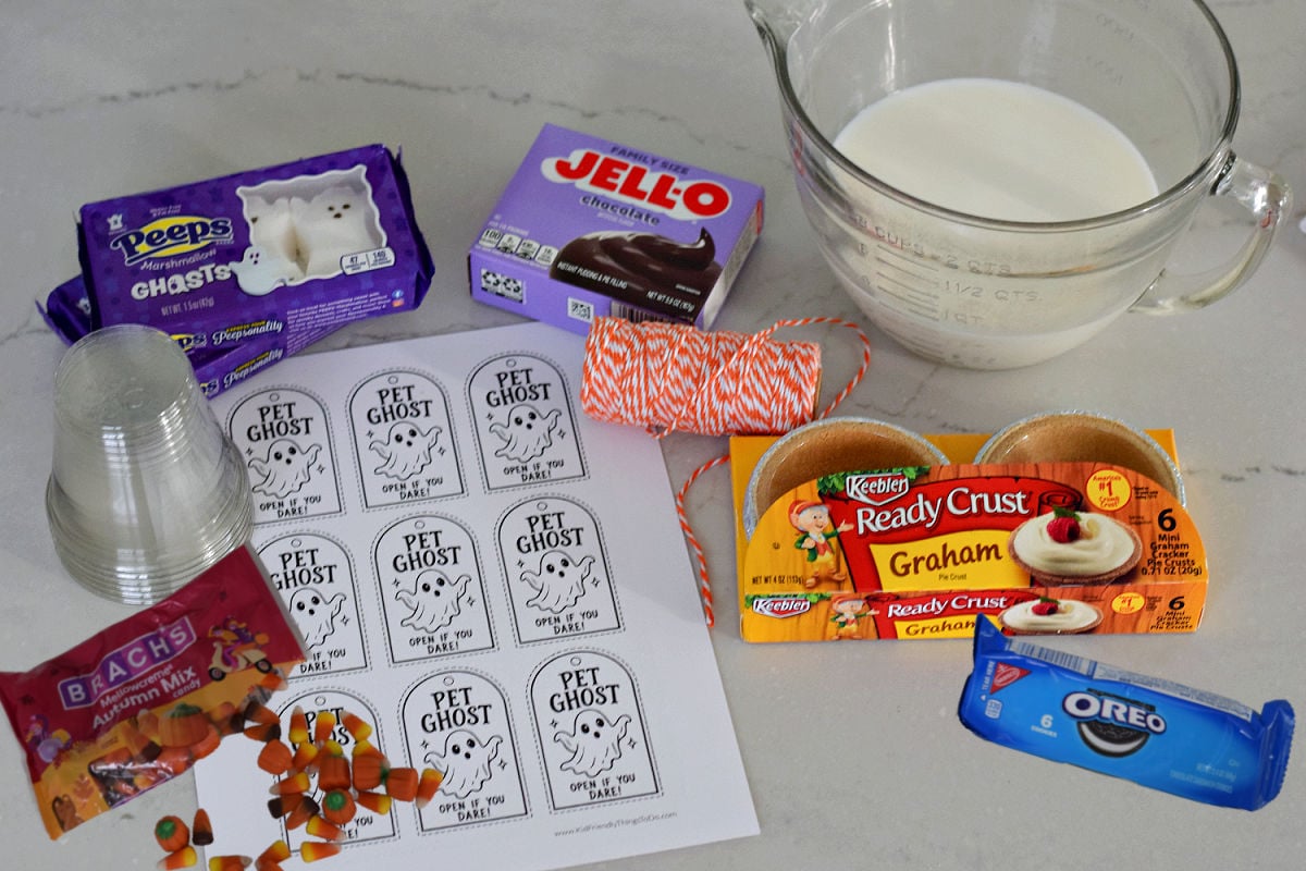Ghost Peeps, chocolate pudding mix, milk, mini graham cracker crusts, Oreos, autumn candy mix, clear cups, orange twine, and printable Pet Ghost tags.