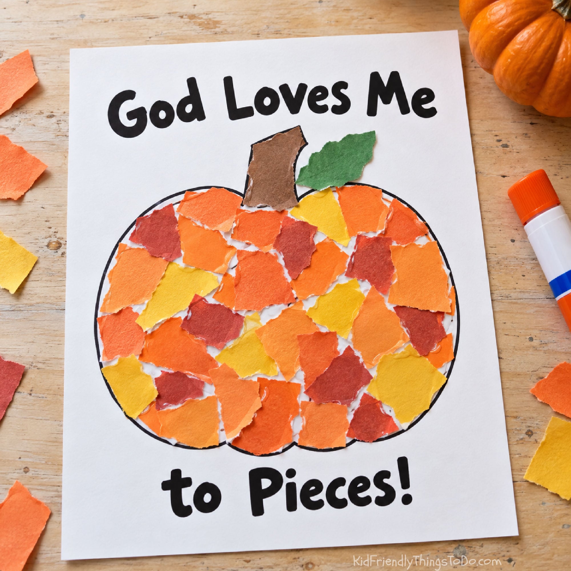 God Loves Me to Pieces pumpkin craft filled with orange, yellow, and rust-colored torn paper, with a brown stem and green leaf.