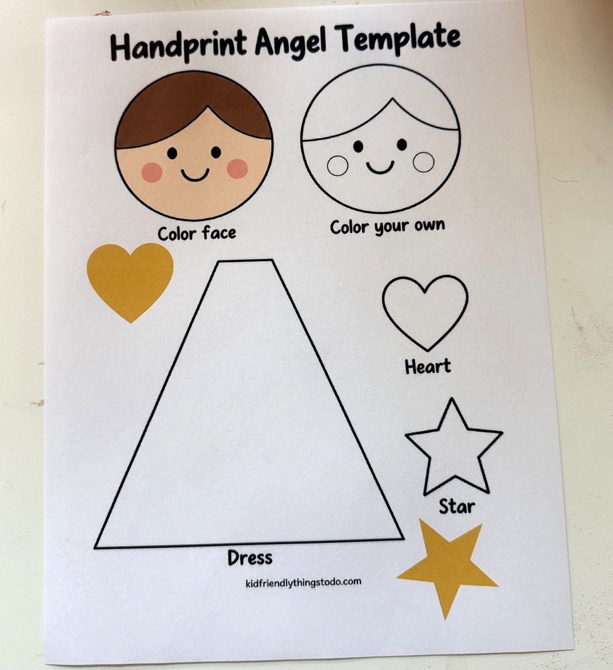 Printed angel template with colored and outline faces, a dress pattern, and gold and outline heart and star pieces