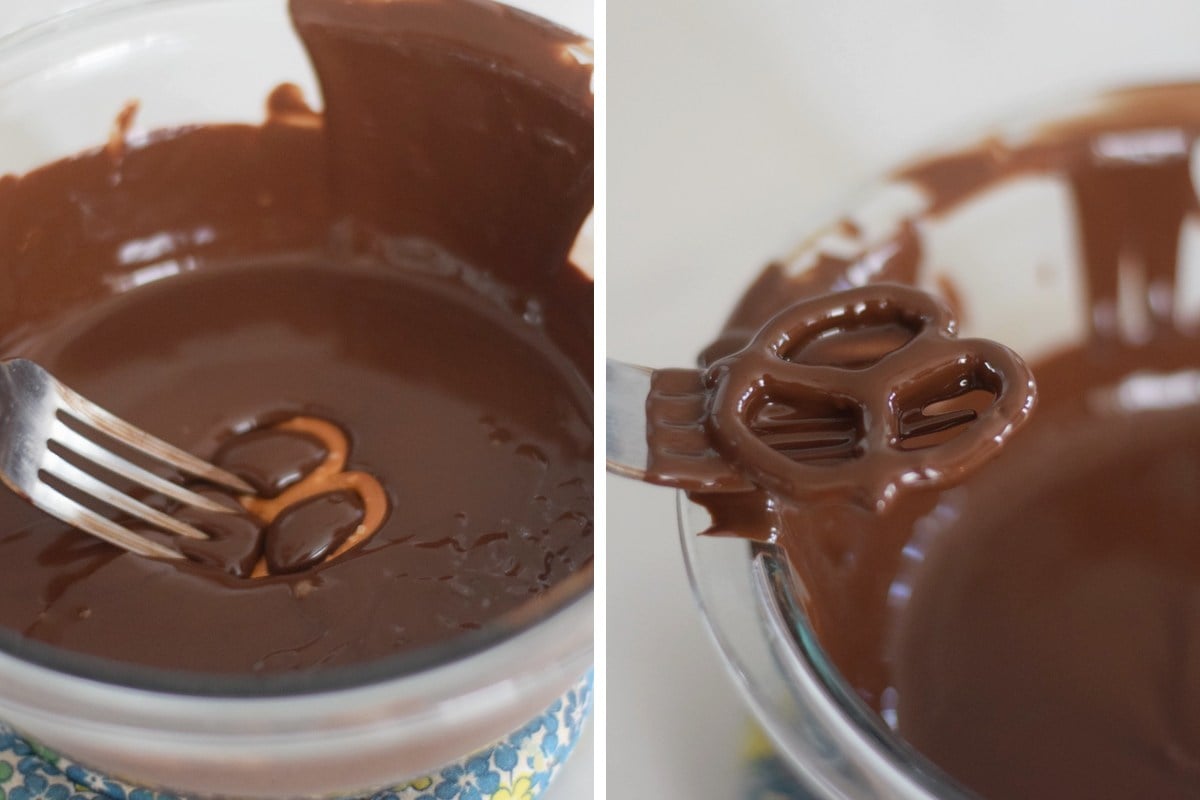 Dipping a pretzel into melted dark chocolate and lifting it with a fork to drain the excess.