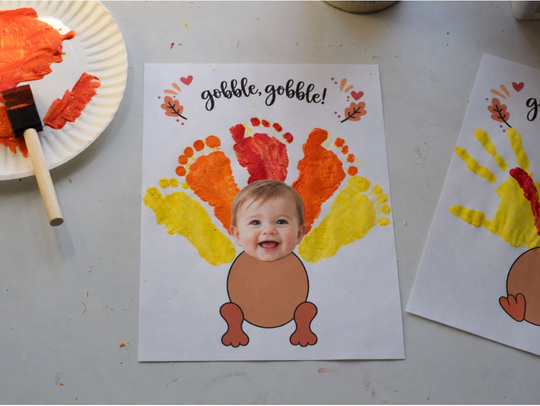 Footprint turkey craft with four colorful painted baby footprints and a photo keepsake