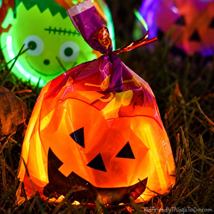 Glowing Halloween treat bags hidden in the grass for a nighttime candy hunt.
