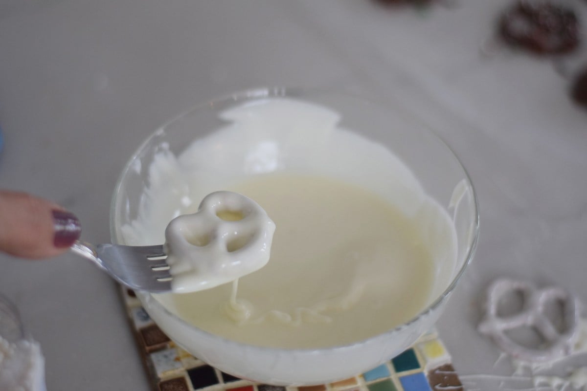 Dipping white chocolate pretzels in melted white candy melts.